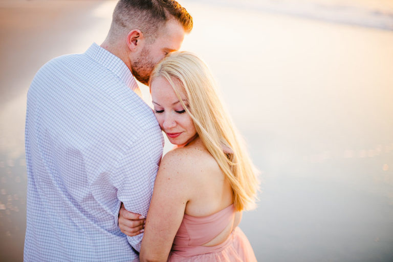 couple embrace during luminous sunrise engagement session at the jersey shore